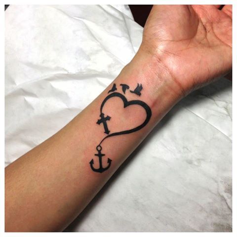 Black Heart With Anchor, Cross And Flying Birds Tattoo On Left Wrist