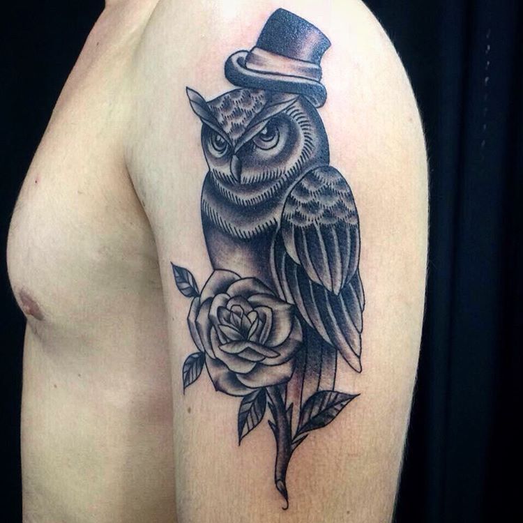 Black Ink Hat On Owl With Rose Tattoo On Man Left Shoulder