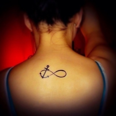 Black Ink Infinity With Anchor Tattoo On Girl Upper Back