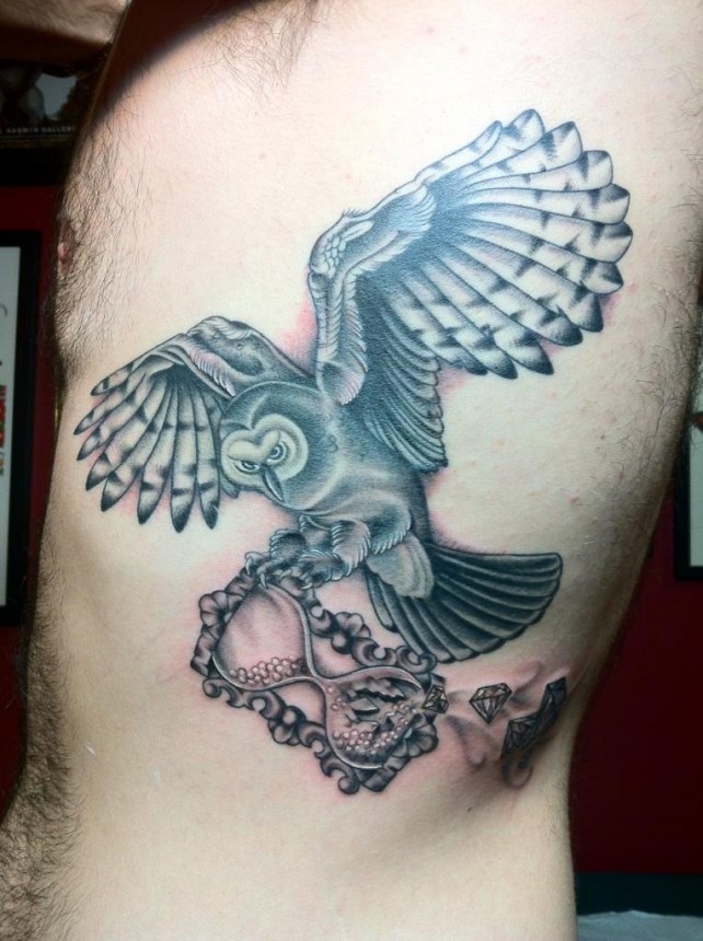 Black Ink Owl With Hourglass Tattoo On Left Side Rib