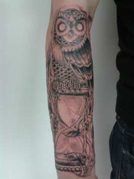 Black Ink Owl With Hourglass Tattoo On Right Arm