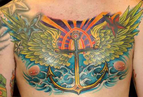 Colorful Traditional Anchor With Wings And Nautical Stars Tattoo On Man Chest