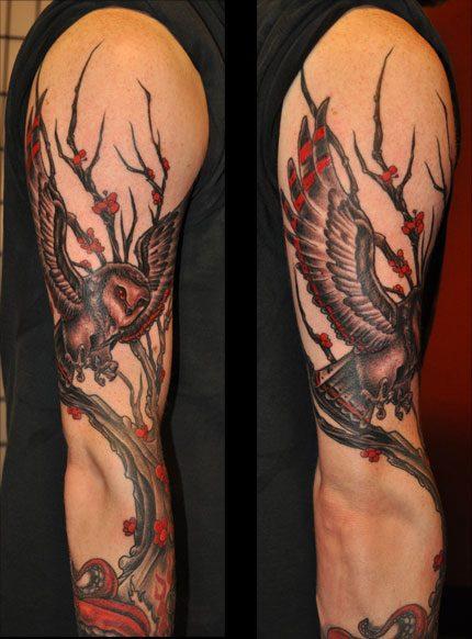Red And Black Flying Owl With Tree Tattoo On Man Right Full Sleeve
