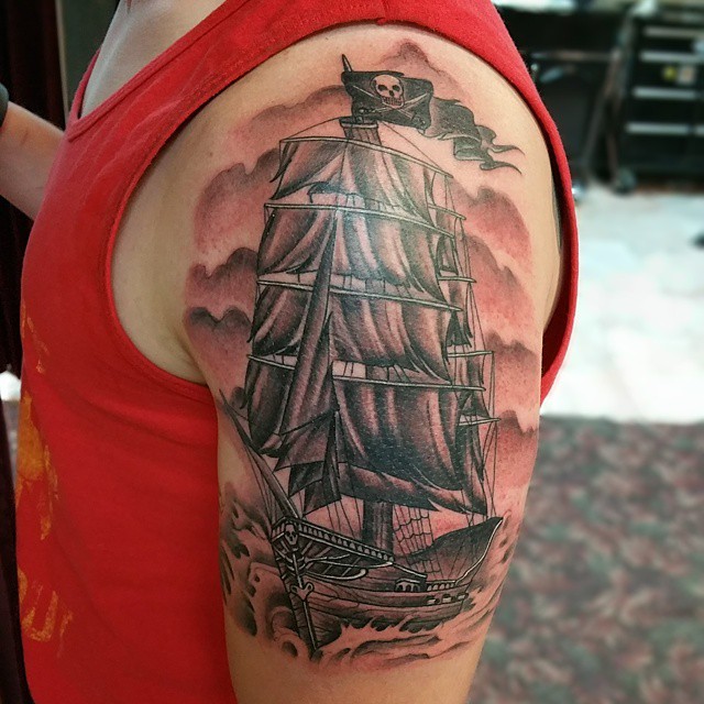 Black Ink Pirate Ship Tattoo On Man Left Shoulder