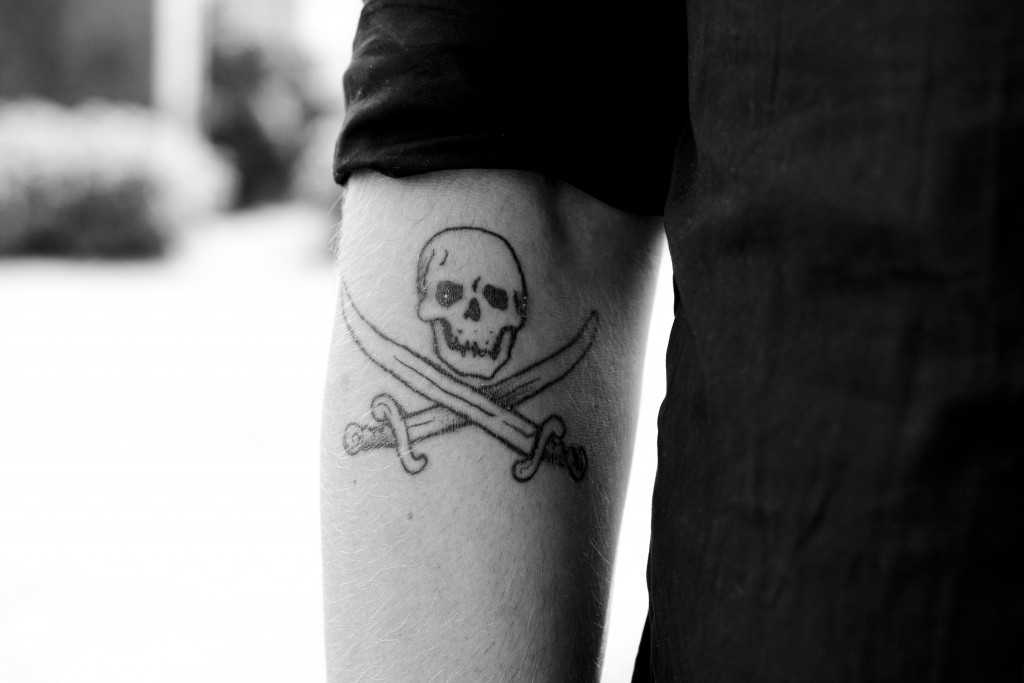 Black Outline Pirate Symbol Tattoo On Left Forearm