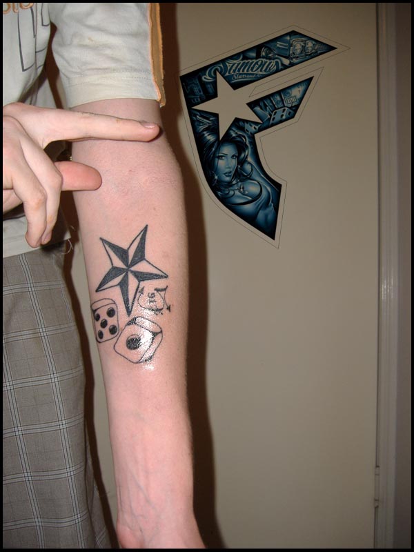 Dice And Nautical Star Tattoo On Forearm