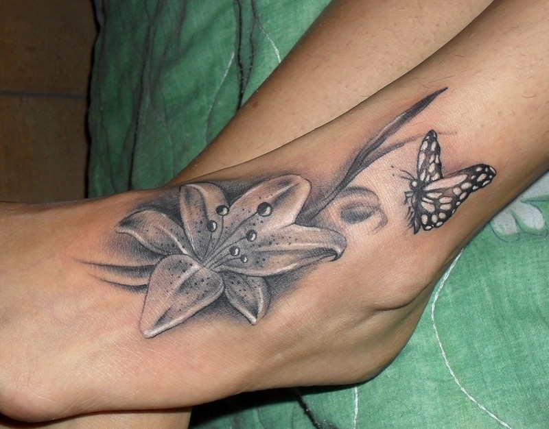 Black And Grey Lily Flower With Butterfly Tattoo On Left Foot