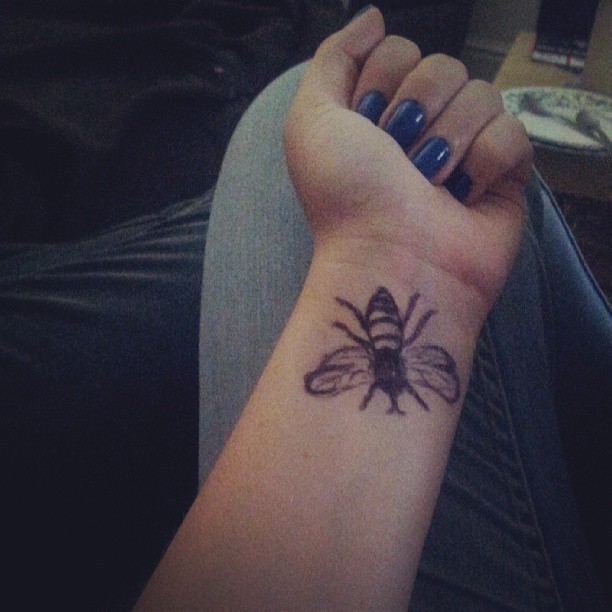 Black Ink Bamblebee Tattoo On Women Left Wrist