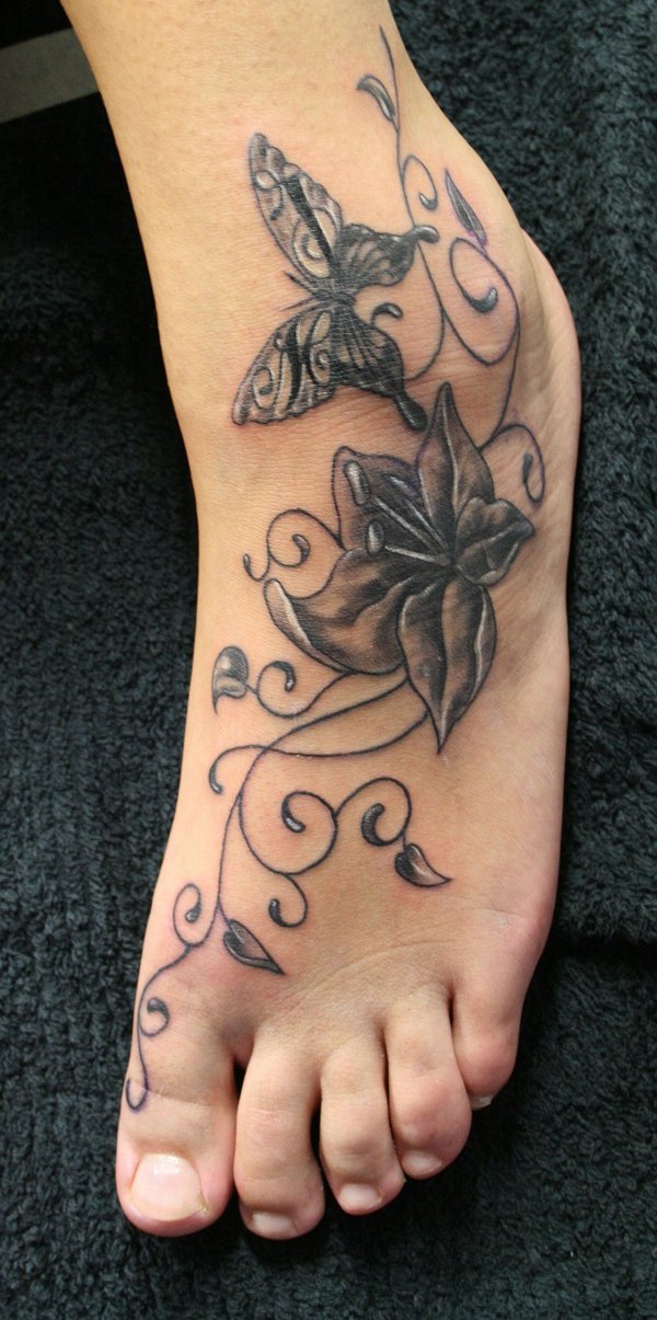 Black Ink Lily Flower With Flying Butterfly Tattoo On Left Foot