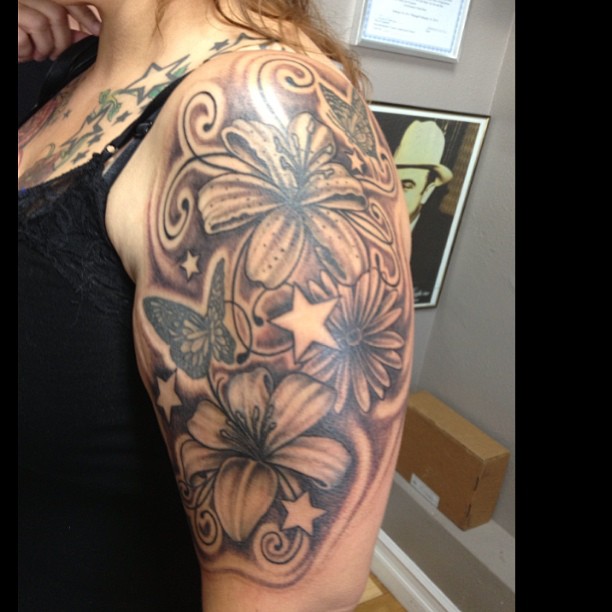 Black Ink Lily Flowers With Flying Butterflies Tattoo On Women Left Upper Arm