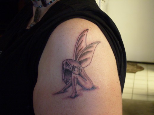 Black Ink Small Fairy Tattoo On Left Shoulder