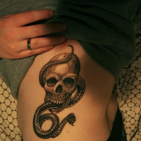 Black Ink Snake In Skull Tattoo On Left Side Rib