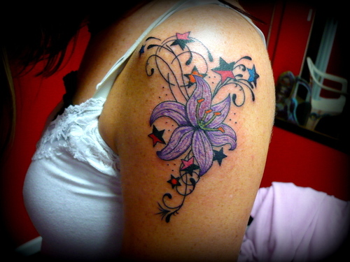 Colored Stars And Purple Lily Tattoo On Left Shoulder