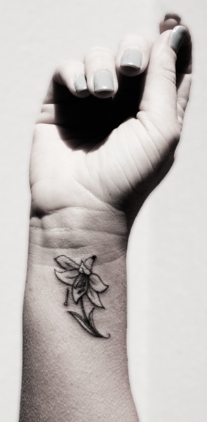 Cool Black Ink Lily Flower Tattoo On Girl Right Wrist