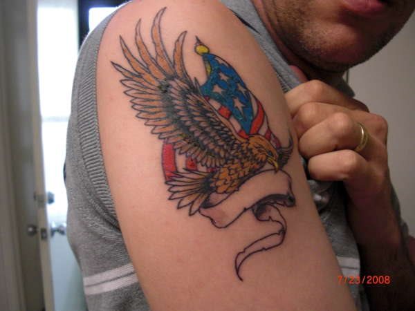 Cool Flying Eagle With USA Flag And Ribbon Tattoo On Right Shoulder
