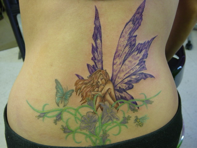 Fairy With Flying Butterflies And Flowers Tattoo On Lower Back