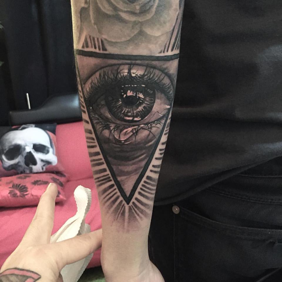 Black And Grey Crying Eye In Triangle Tattoo On Left Arm