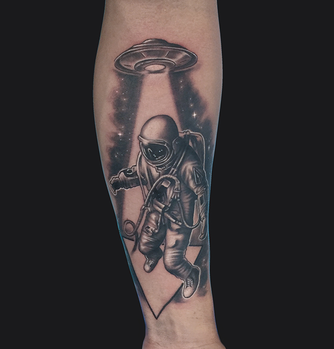 Black Ink Astronaut With UFO Tattoo On Forearm By Marc Durrant