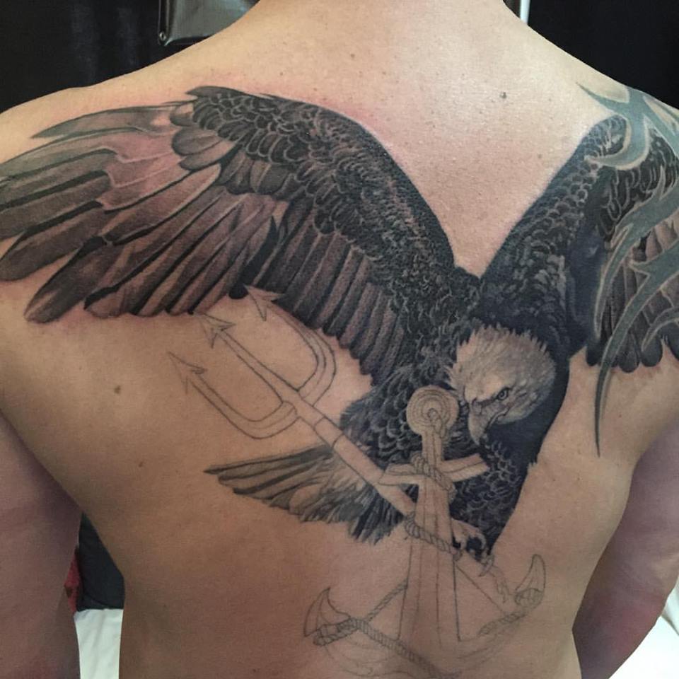 Black Ink Flying Eagle With Trident Tattoo On Man Upper Back