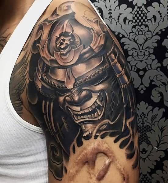 Black Ink Samurai Head Tattoo On Man Left Shoulder