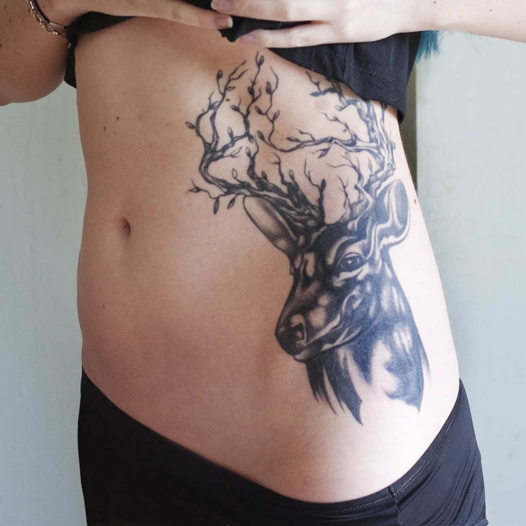 Girl Showing Her Tribal Deer Tattoo On Side Rib