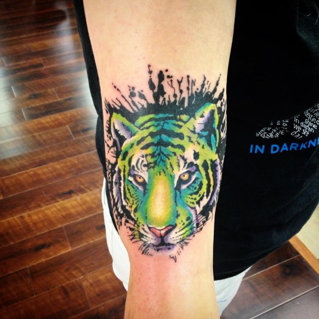Green And Blue Ink Tiger Face Tattoo On Arm