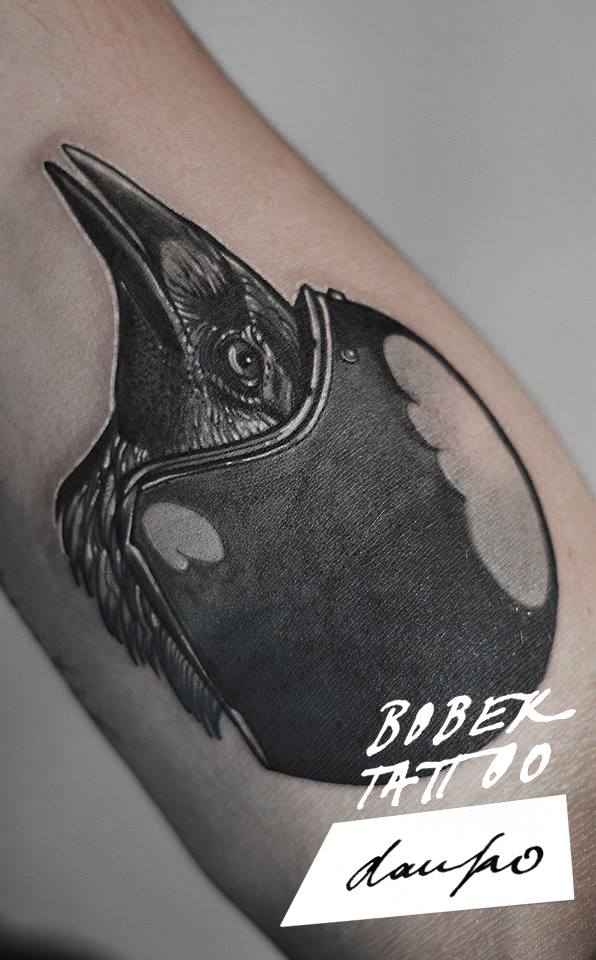 Black Ink Helmet On Crow Head Tattoo On Bicep