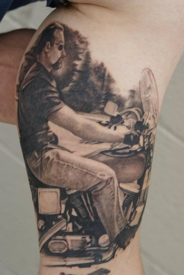 Black Ink Man On Motorcycle Tattoo On Bicep By Tom Renshaw