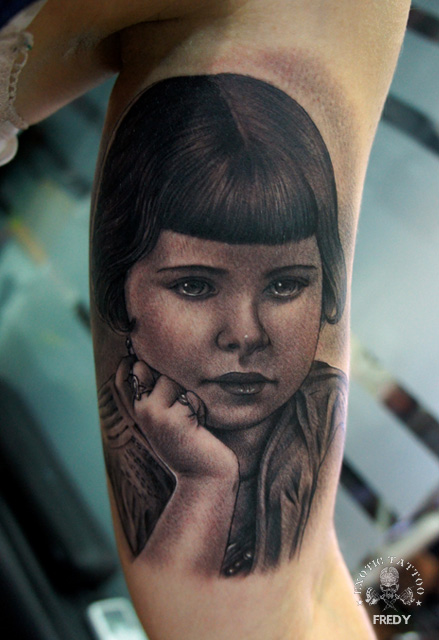 Cute Black Ink Girl Face Portrait Tattoo On Left Bicep By Fredy