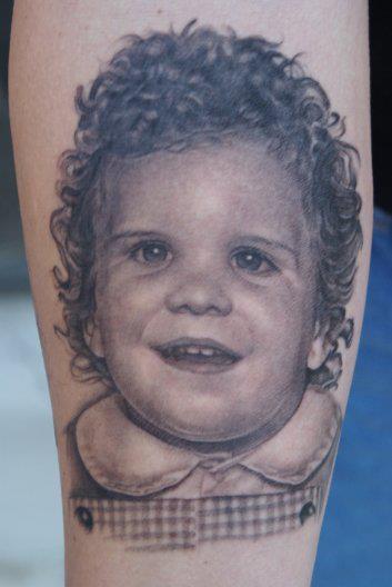 Grey Ink Curly Haired Baby Boy Portrait Tattoo On Forearm By Tom Renshaw