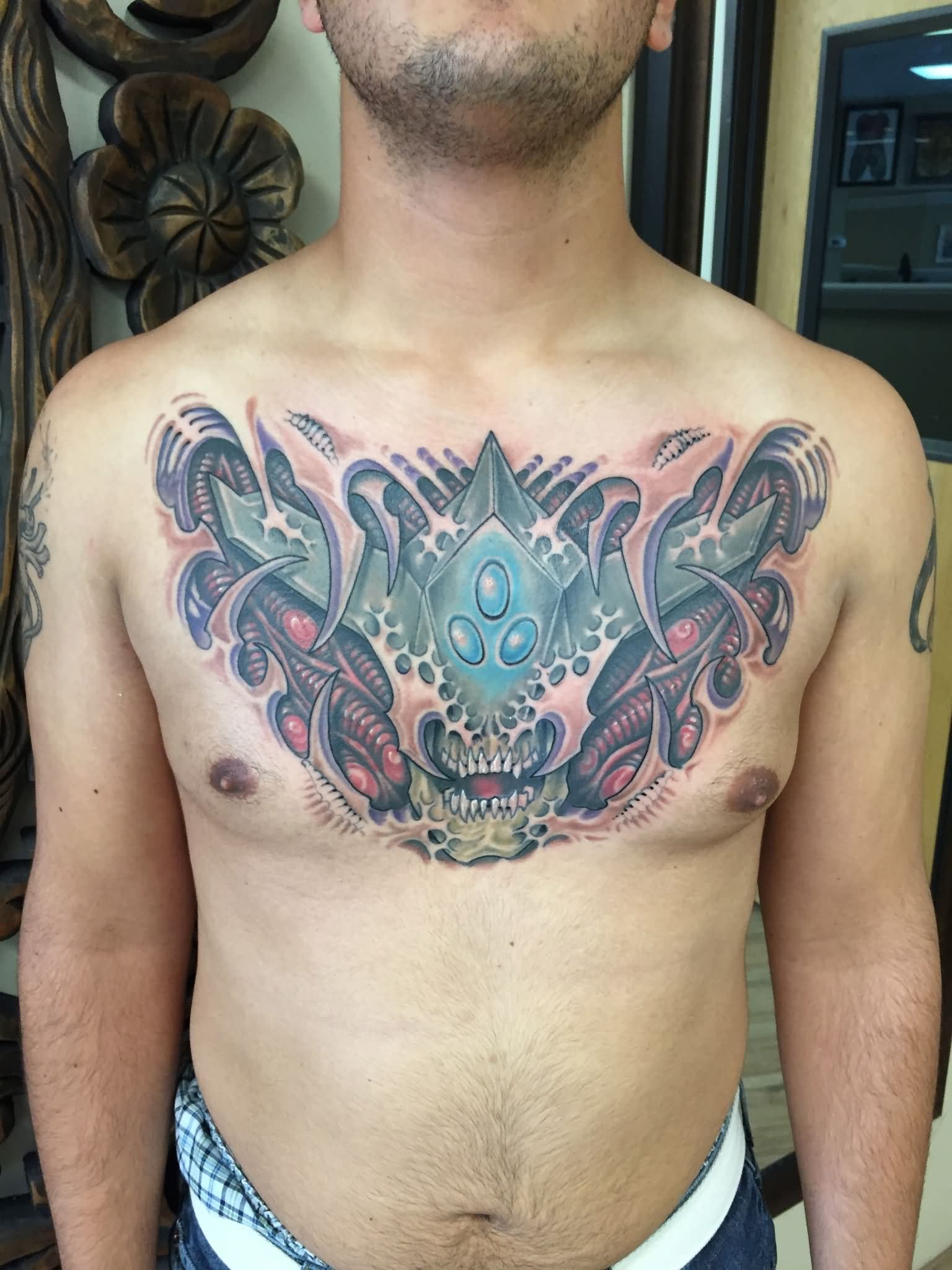 Ripped Skin Alien Face Tattoo On Man Chest By Daniel Troyer