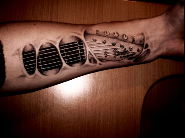 Black And Grey Ripped Skin Guitar Tattoo On Left Forearm