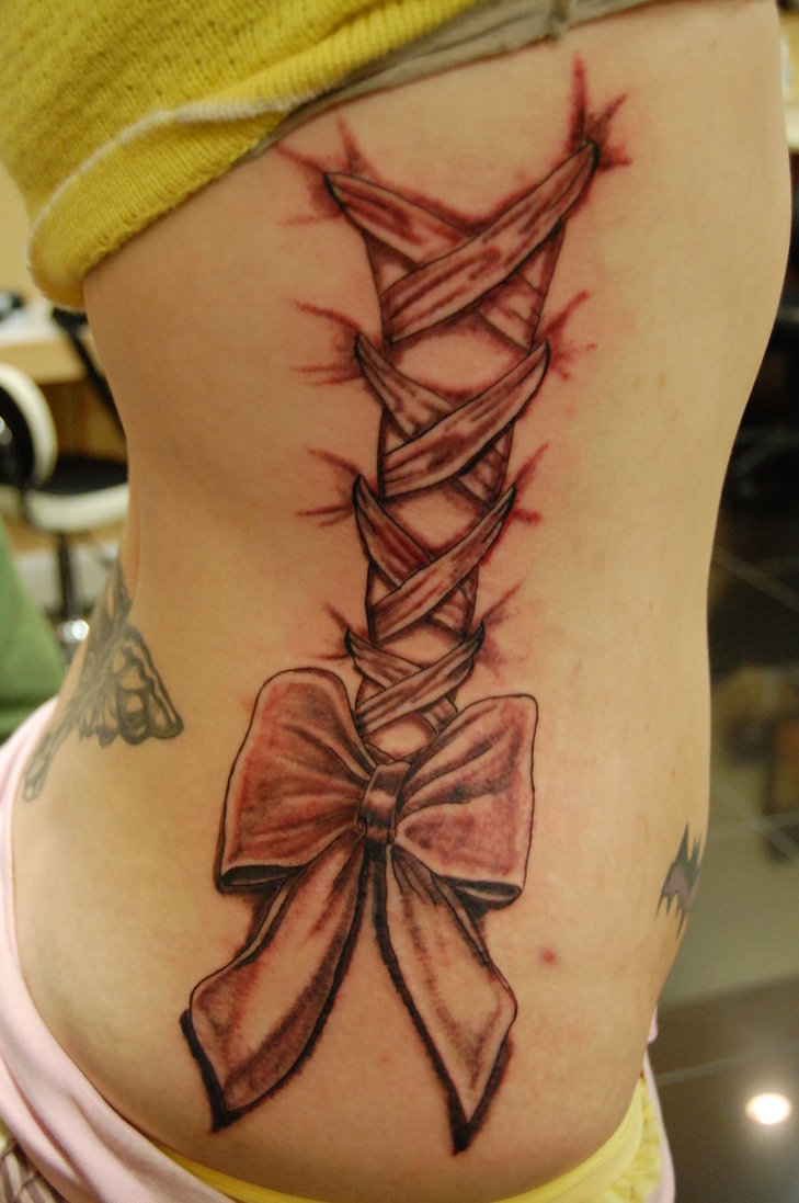 Black Ink Corset With Bow Tattoo On Girl Right Side Rib