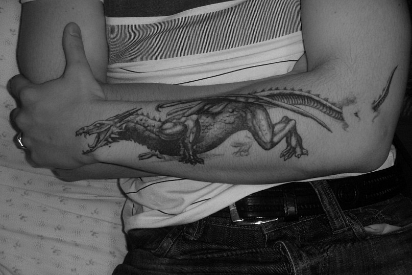 Black Ink Dragon Tattoo On Man Left Forearm