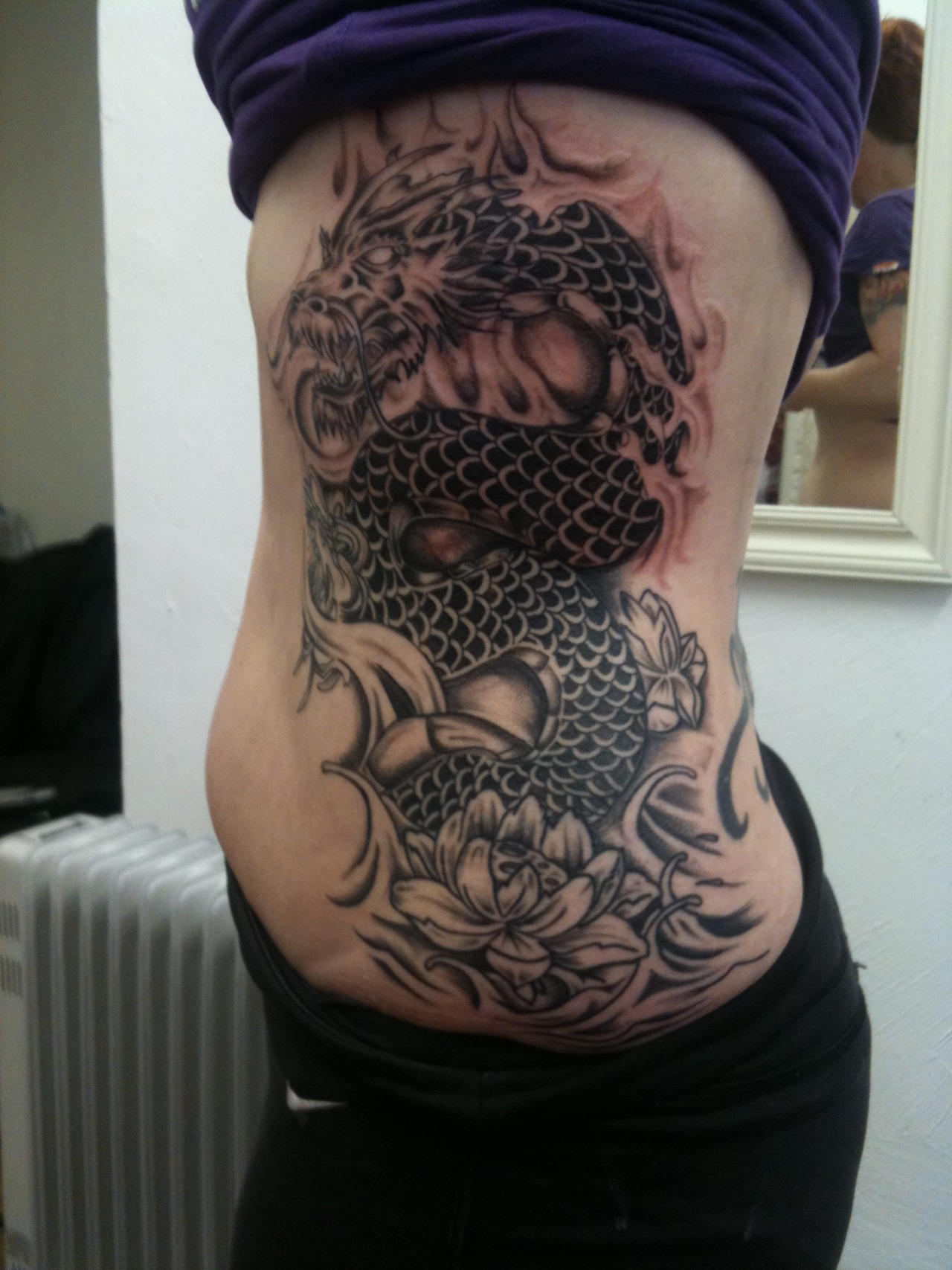 Black Ink Dragon With Lotus Flower Tattoo On Right Side Rib