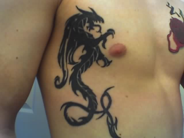 Black Ink Tribal Dragon Tattoo On Man Right Side Rib