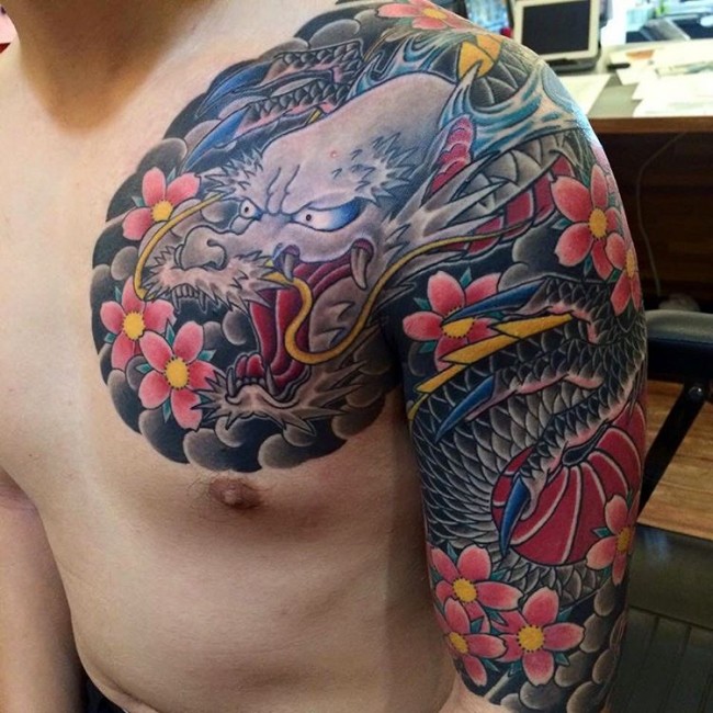 Colorful Traditional Dragon With Flowers Tattoo On Left Shoulder And Half Sleeve