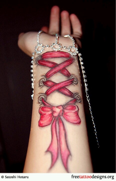 Red Ink Corset With Bow Tattoo On Left Wrist