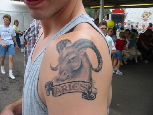 Black And Grey Aries With Banner Tattoo On Man Left Shoulder