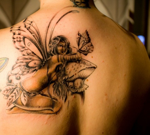 Black Ink Fairy On Mushroom Tattoo On Upper Back