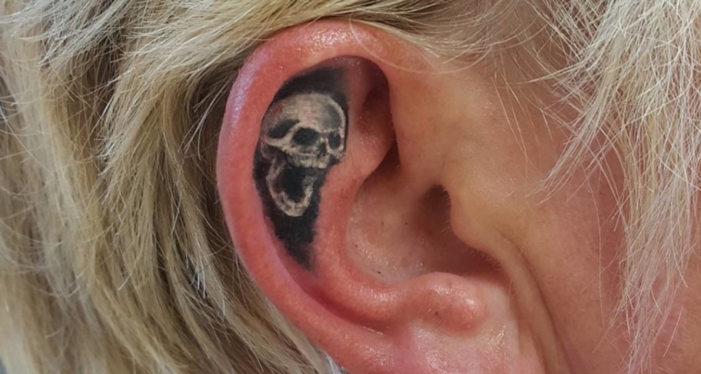 Black Ink Skull Tattoo On Girl Right Ear