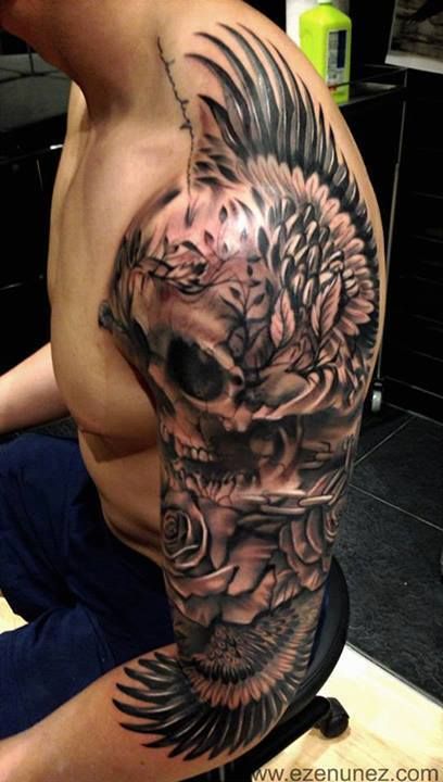 Black Ink Skull With Wings Tattoo On Man Left Upper Arm