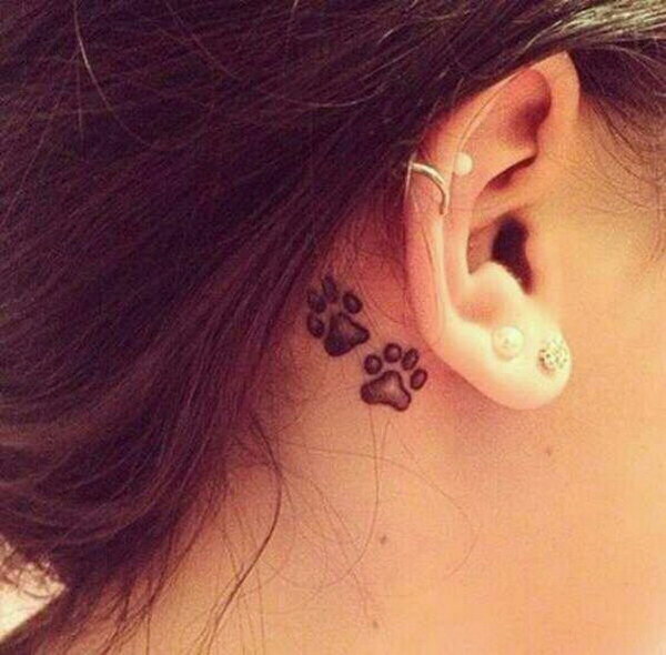 Black Ink Two Paw Prints Tattoo On Girl Right Behind The Ear