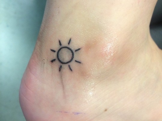 Black Outline Sun Tattoo On Right Ankle
