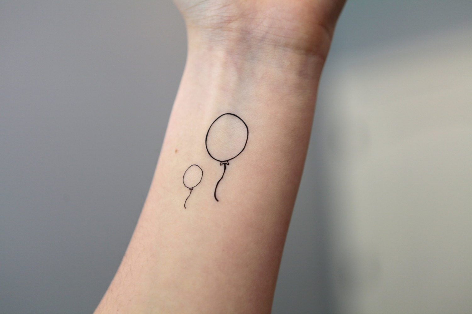 Black Outline Two Balloons Tattoo On Left Wrist