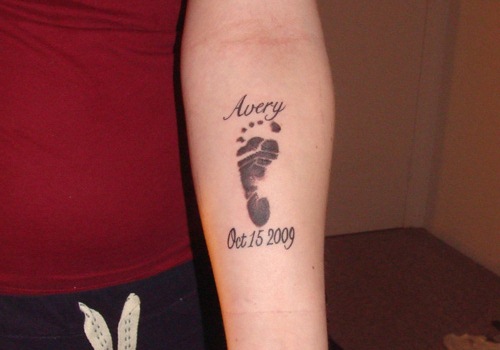 Avery - Memorial Black Ink Footprint Tattoo On Forearm
