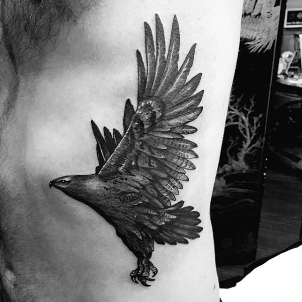 Black Ink Flying Hawk Tattoo On Man Left Side Rib
