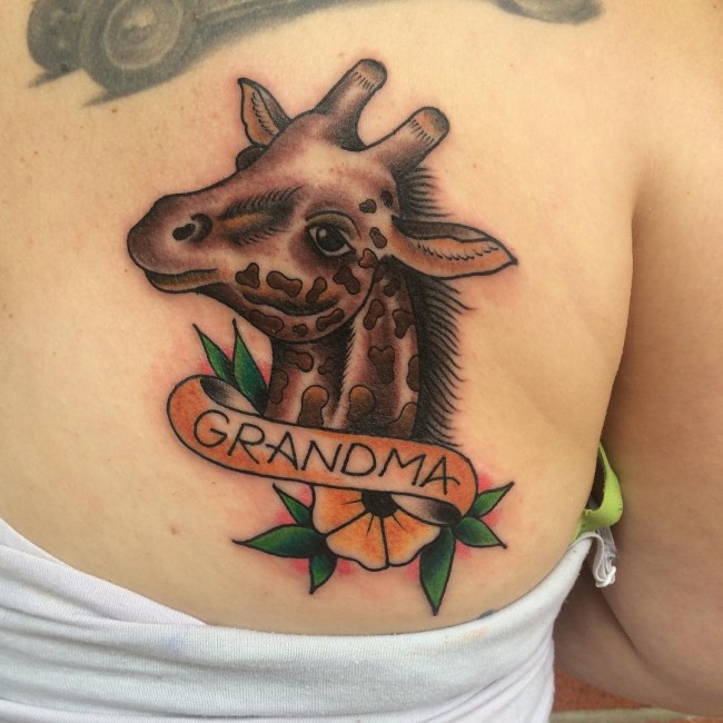 Black Ink Giraffe Head With Banner And Flower Tattoo On Back Shoulder