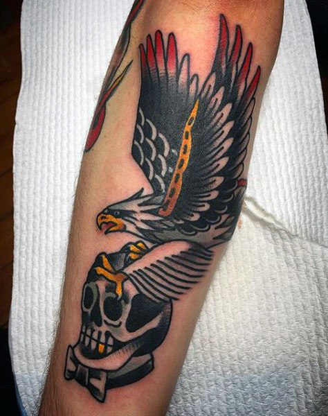 Bald Eagle Catching Skull In Claws Tattooed On Forearm