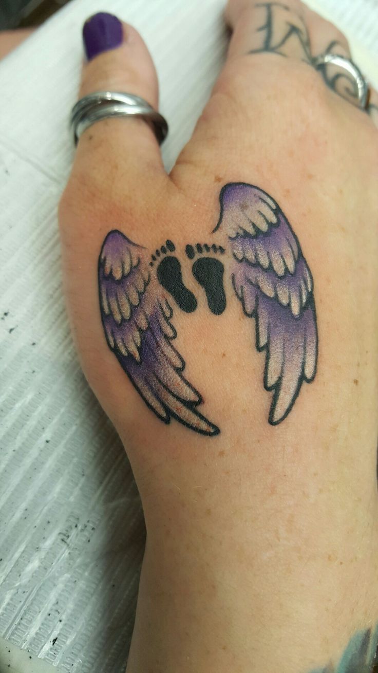 Little black feet with purple angel wings tattoo on hand
